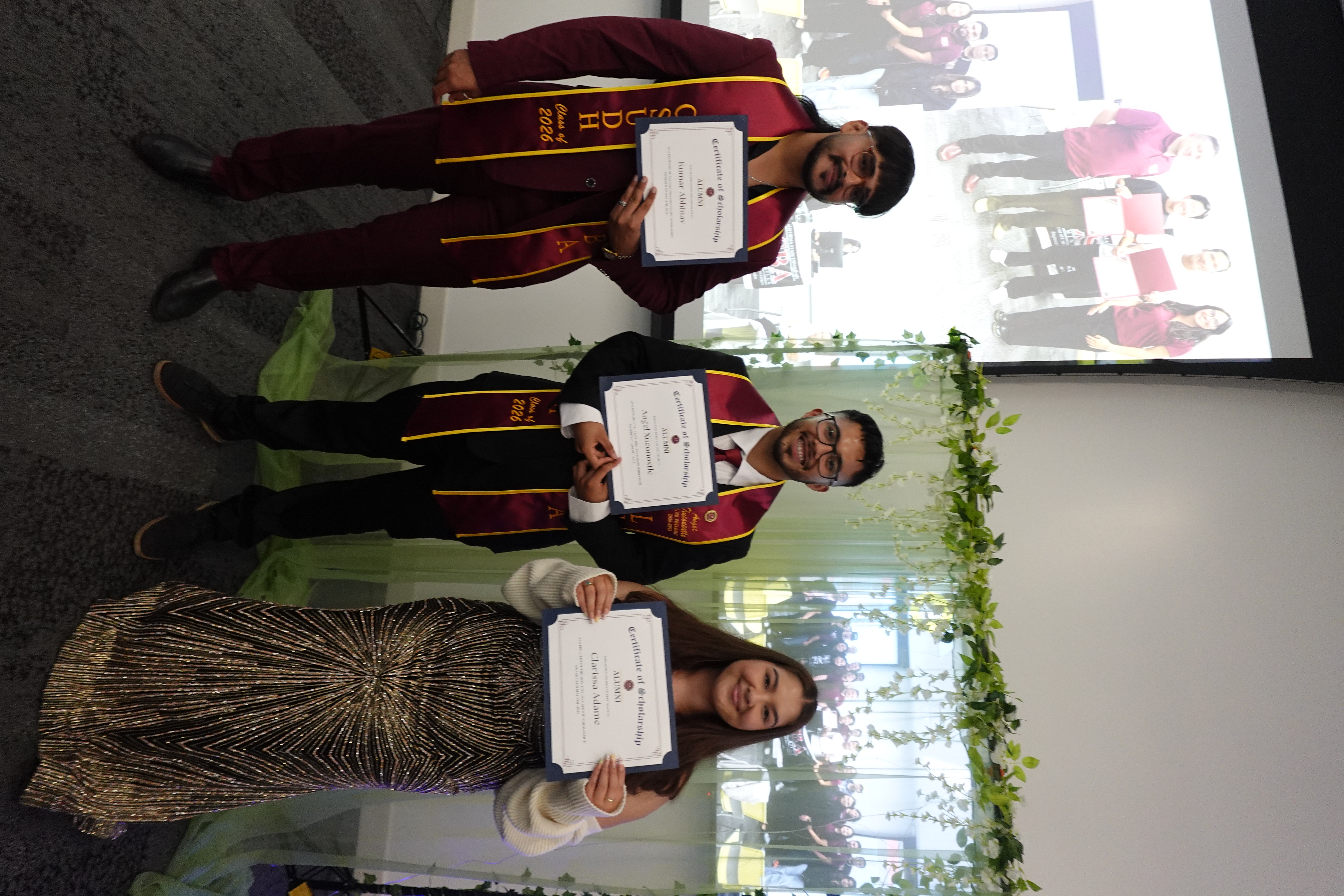Three LSBA alumni scholarship recipients wearing maroon and gold graduation sashes and holding their certificates at the LSBA Banquet.